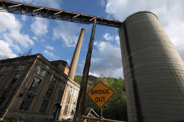 Concrete silo with a sign in front of it that reads, "BRIDGE OUT"