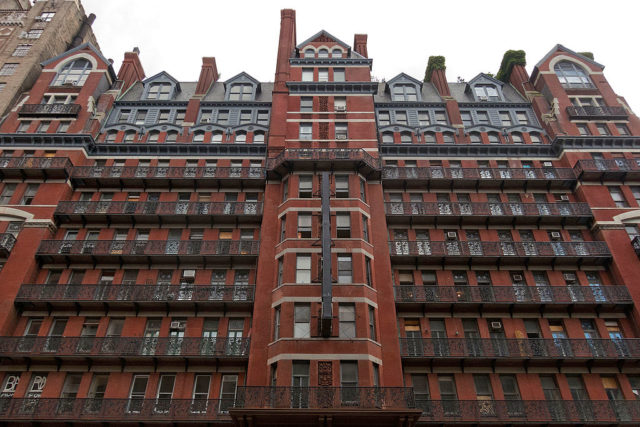 Red exterior of the Hotel Chelsea with iron railings outside the windows.