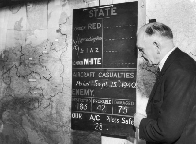 Man standing beside a chalkboard with a variety of statistics written on it