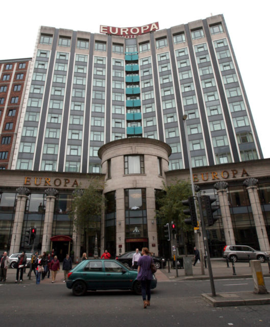 Exterior of the Europa Hotel with people and cars out front.