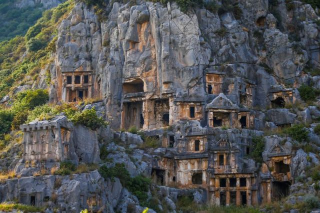 Various different square entrances carved into a rock face at different levels.