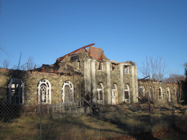 The outside of a decrepit building with a fallen in roof