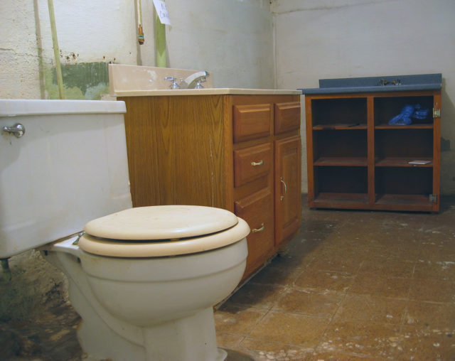 A toilet beside broken cabinets