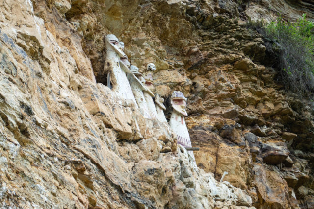 Sarcophagi of Carajía, tall statues set into a cliff wall.