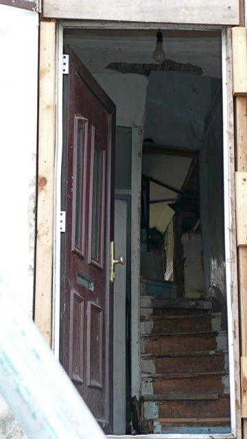 An open door showing a dilapidated staircase