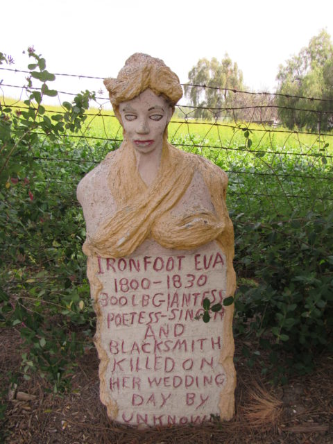 A tombstone sculpture with a woman's head and chest on the top of it