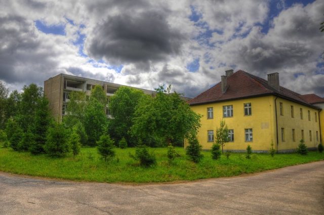 Abandoned yellow house set in front of an abandoned apartment building.