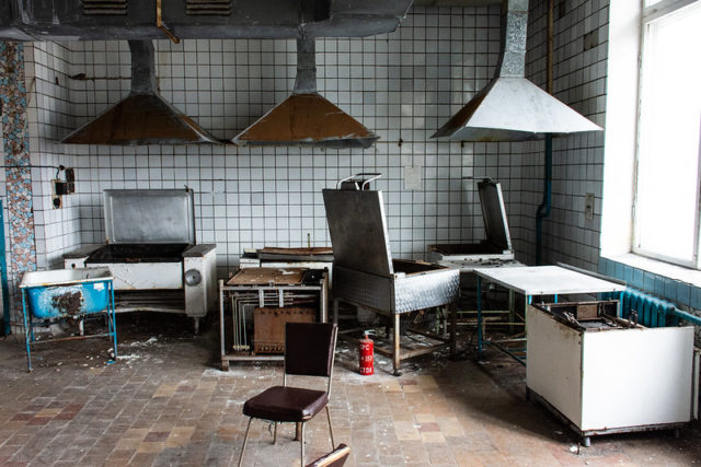 Abandoned kitchen with partially destroyed appliances.