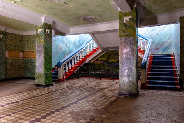 Stairwell inside a building with paintings all over the wall.