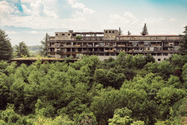 Abandoned building emerging from the middle of a large forest.