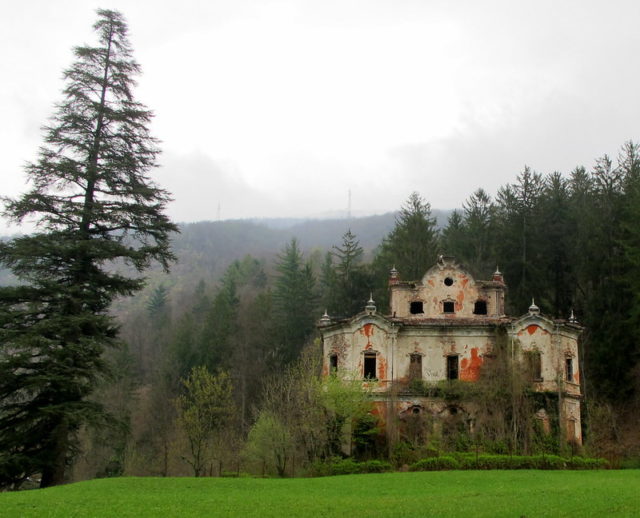 Distanced view of the Villa de Vecchi surrounded by trees.