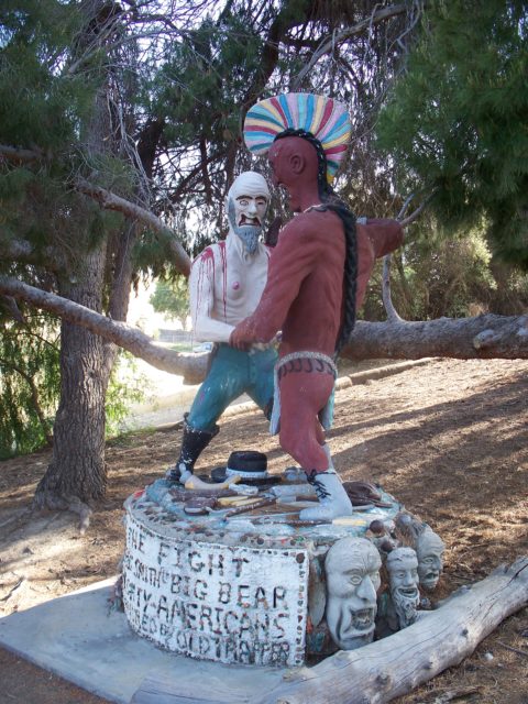 A sculpture of a white man and a brown man fighting