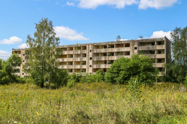 Abandoned apartment building in the middle of a grass field.