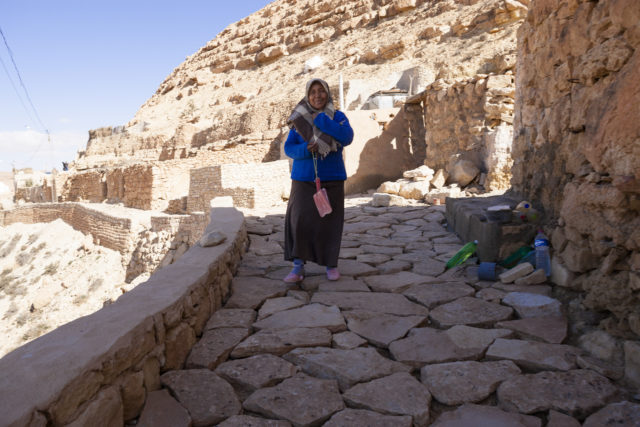 A woman standing on a rocky path in a mountain village