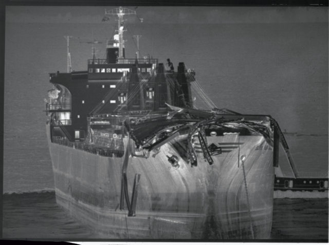 A freight ship with pieces of collapsed bridge on its bow
