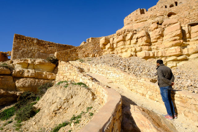 A man standing at the bottom of a rocky hill on a mountain