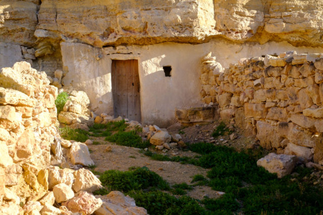 The view of a cave-dwelling with a door and small window