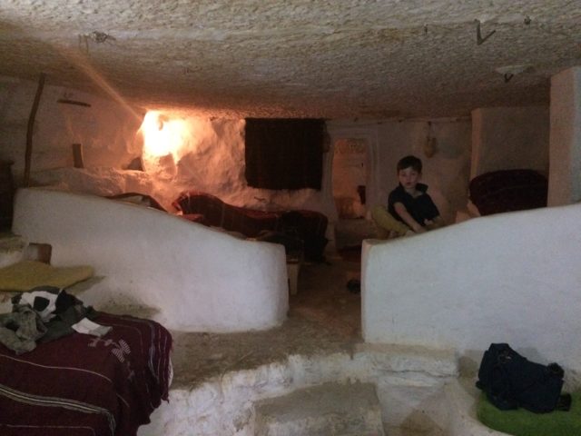 A child standing in a cave house with a tv and furniture