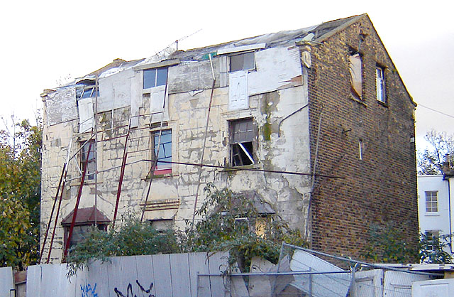 A dilapidated house with a destroyed fence 