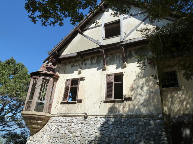 Exterior view of the Mussolini Villa with a wooden turret and wood slat windows.