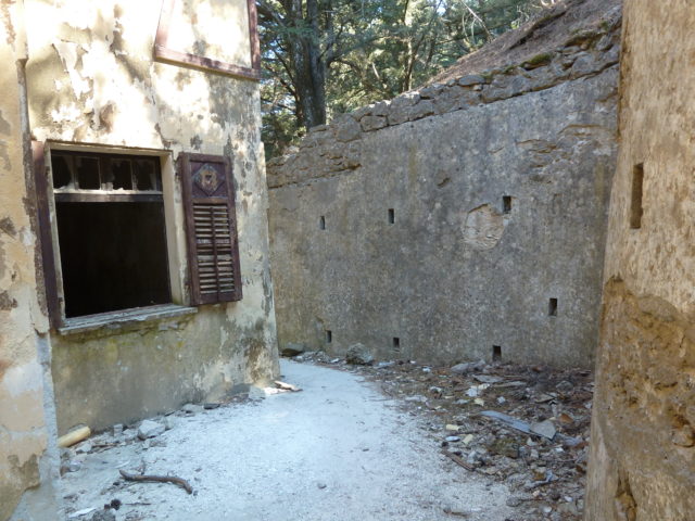 Exterior pathway between the villa and a large concrete wall.