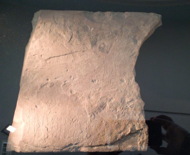 A sandstone slab on display, with etchings of runes on it