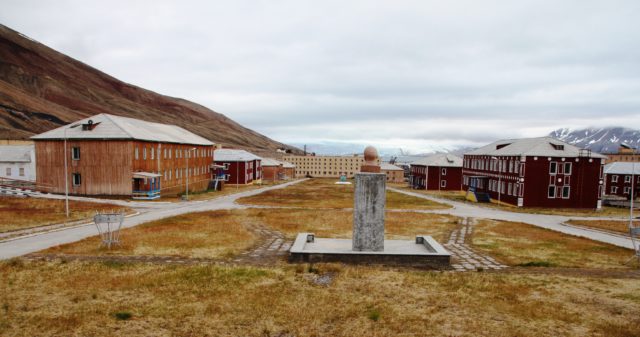 Various red buildings around an open grass courtyard.