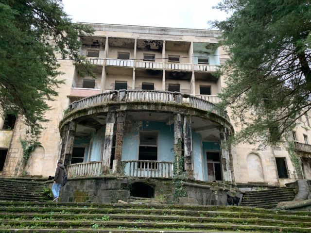 Abandoned building with moss covered stairs leading up to it.