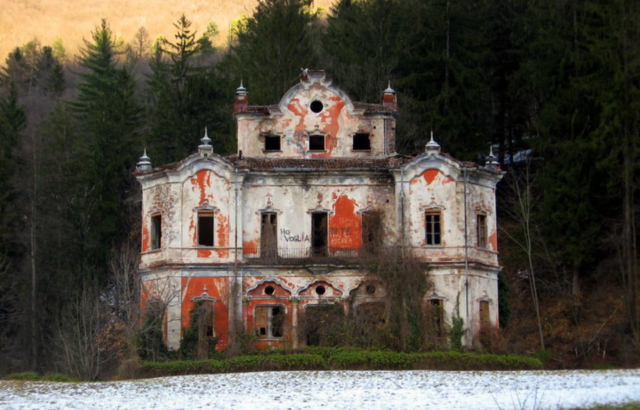 Front view of the Villa De Vecchi, a mansion with red paint peeling off the front.