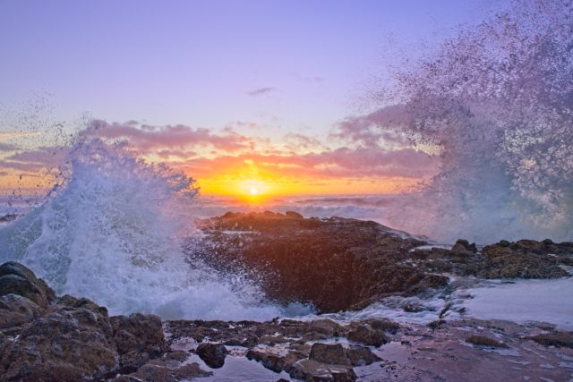 Water splashing around rocks at sunset. 