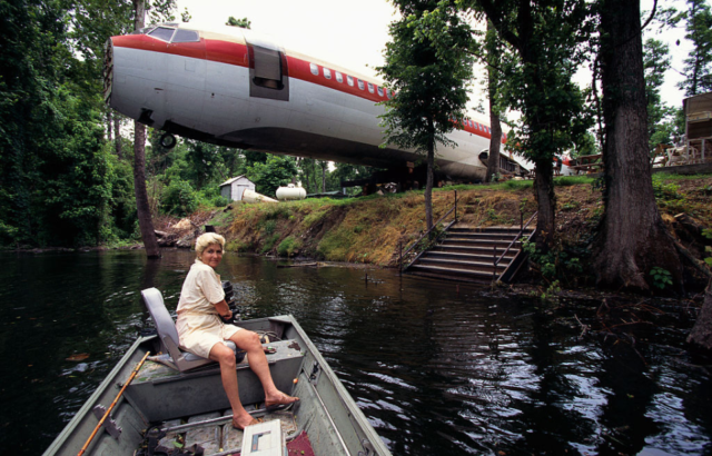 Woman in a boat on water in front of a Boeing 727.