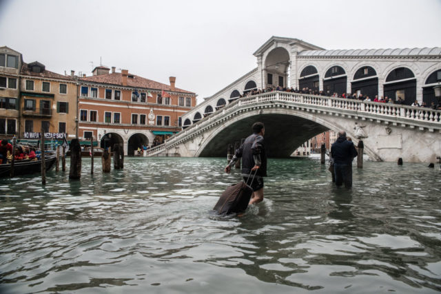 People walak through the flooded streets along the canals in Venice during a 2018 flood