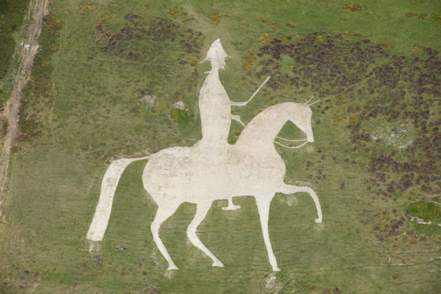 A figure of a man wearing a hat and holding a weapon riding atop a horse carved into a hillside.