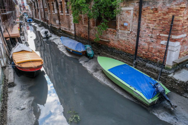 Boats sitting on the banks of the canals where water levels have vastly reduced in Venice