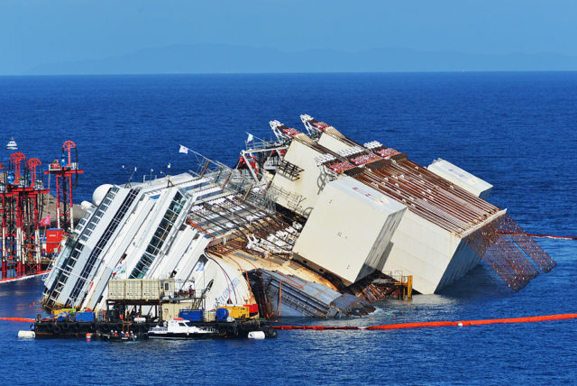 Costa Concordia with caissons attached to her side in the middle of the water.