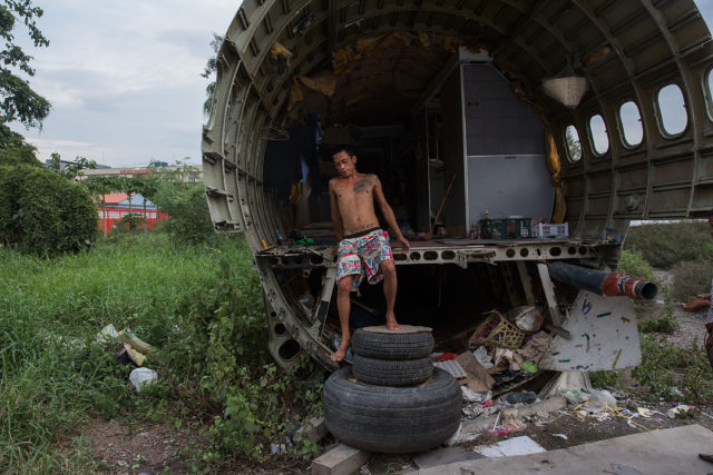 A man stepping out of the remains of a plane that appears to have been sliced in half.