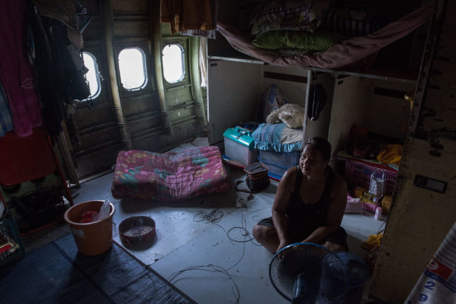 A woman sitting inside a makeshift home inside of a plane cabin. 