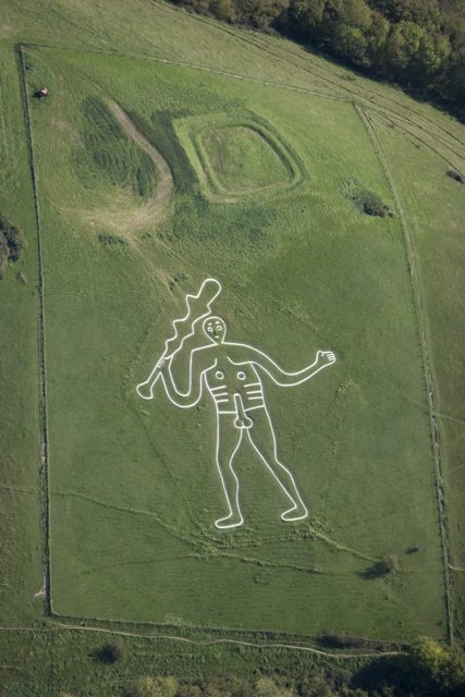 A naked man with erected genitalia holding a club carved into a hillside.