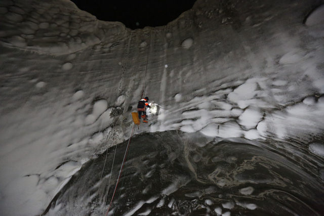 Person scaling down the inside of an icy crater. 