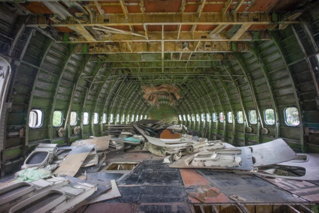View of the inside of an abandoned plane, empty except for some debris.