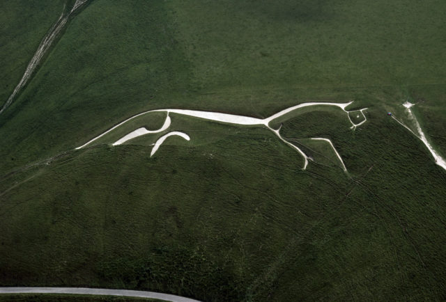 A white minimalistic horse carved into a hillside.
