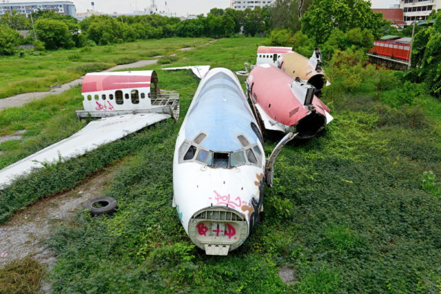 The remains of a damaged plane sitting on a grassy field.