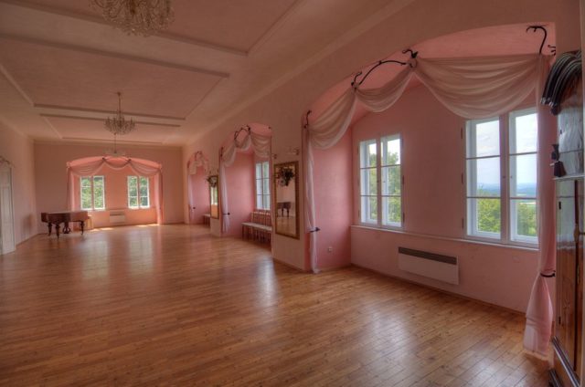 Room with wooden floor, and pink walls and curtains.