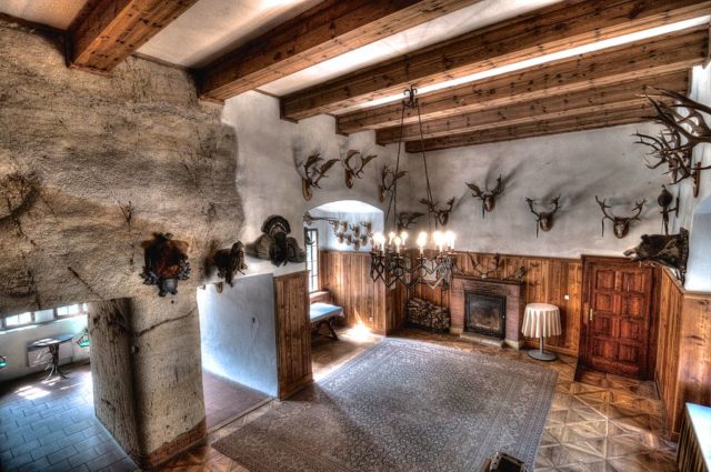 Room with wooden beams, stone walls, and animal heads mounted on the wall.