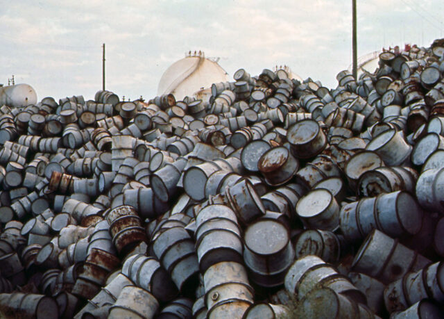 Mountain of rusting metal oil drums.