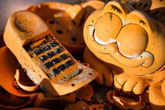 A close up of Garfield phone parts collected in a pile and covered in sand.