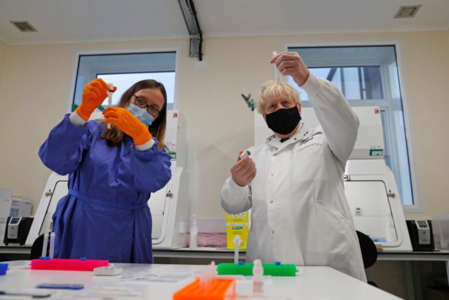 Boris Johnson and Abbie Bown look at lab samples while wearing lab equipment.