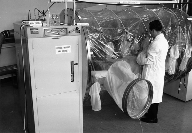 man standing beside a large sized plastic tube in a laboratory.