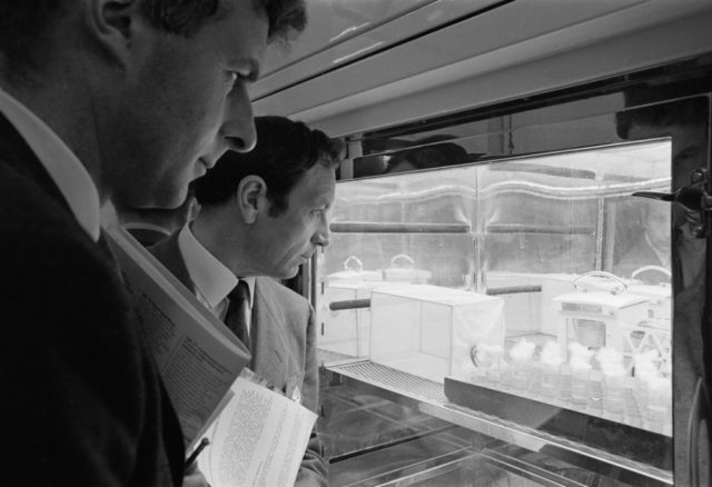 Two men looking through a glass window at scientific materials. 