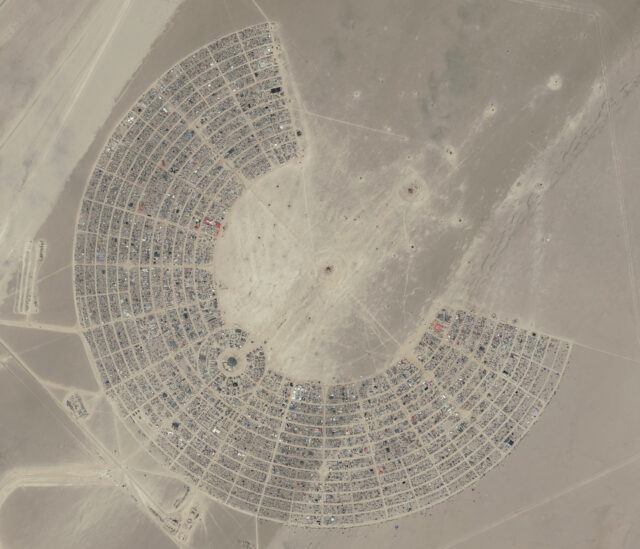 Satellite view of the Burning Man Festival, formed into a semi-circle in a desert.